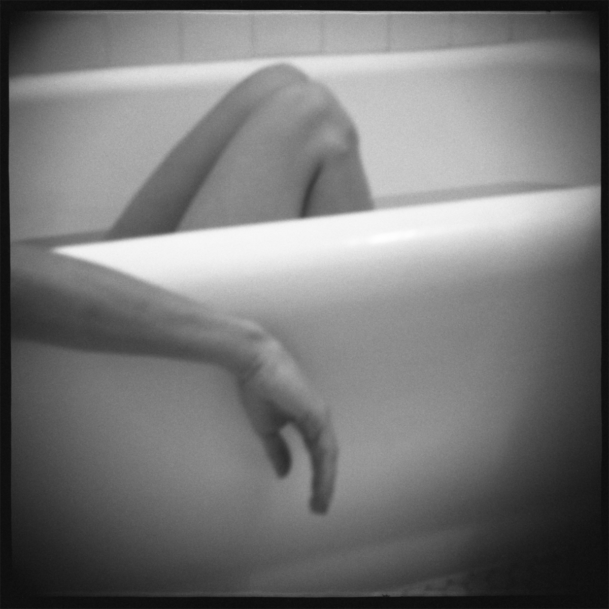 "naked in bath tub in black and white"